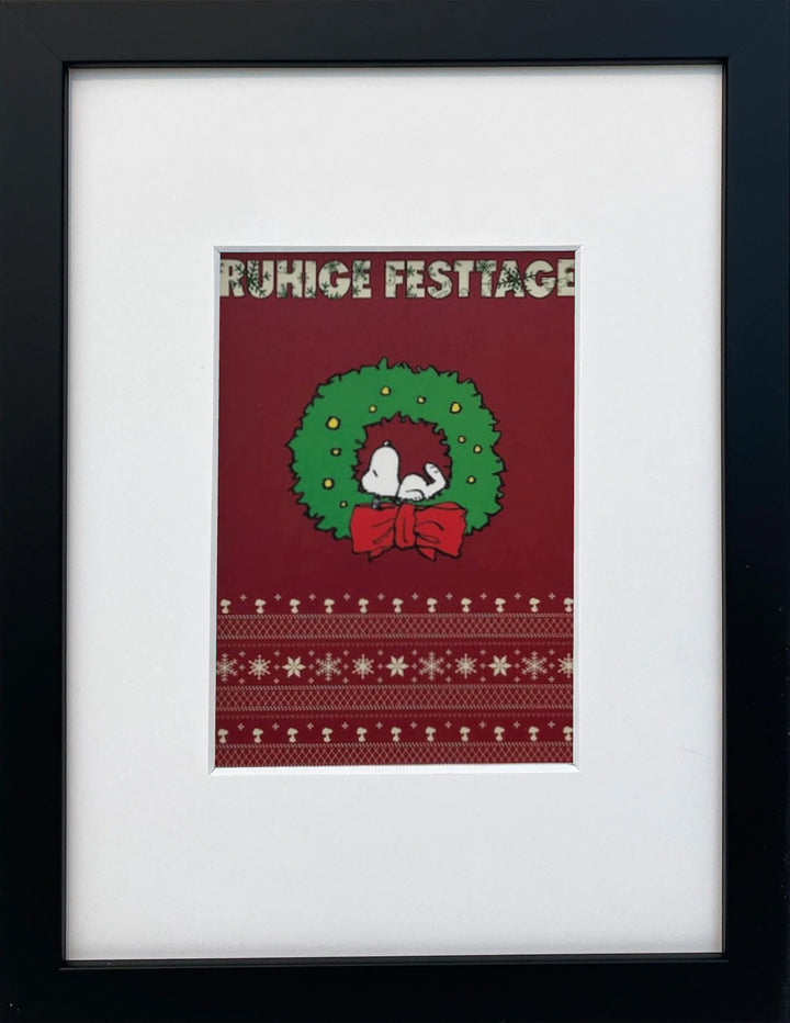 UNICEF-Karte „Ruhige Festtage“ mit Snoopy im Weihnachtskranz als gerahmter Miniprint im schwarzen Holzrahmen